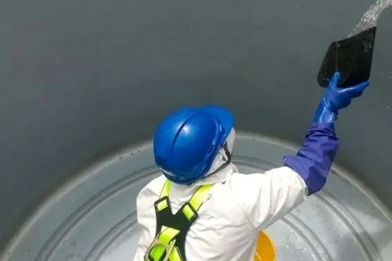 Operario con casco y arnés limpiando el interior de un tanque